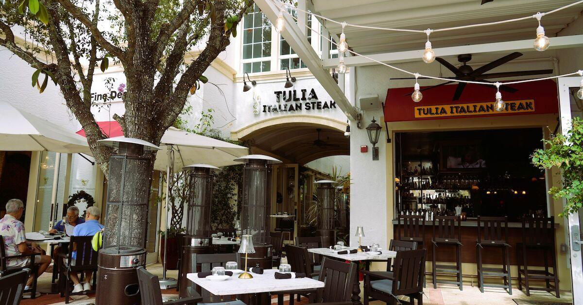 Outdoor restaurant patio with tables, heaters, and string lights.