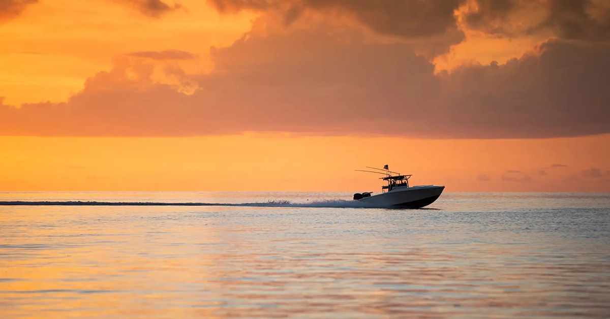 Luxury boat cruising across calm water at sunset near Naples waterfront residences
