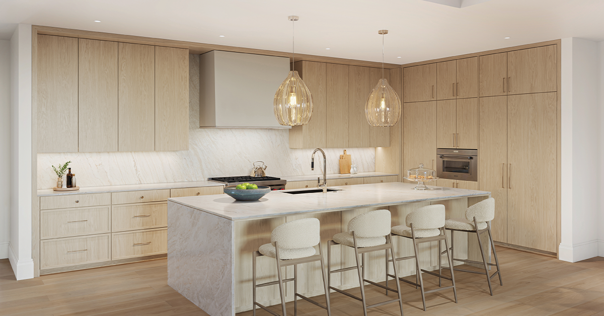 Modern kitchen with light wood cabinets, marble island, and pendant lights.