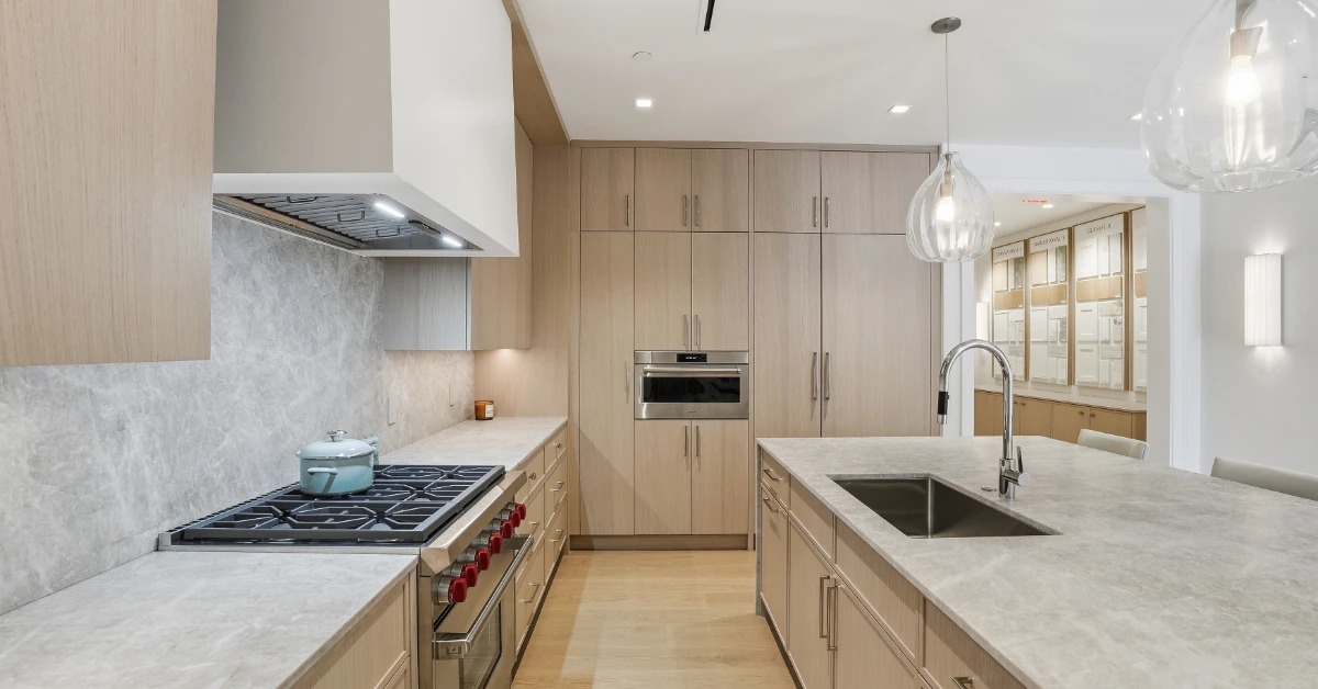 Modern kitchen with light wood cabinets, stone countertops, and central island sink.