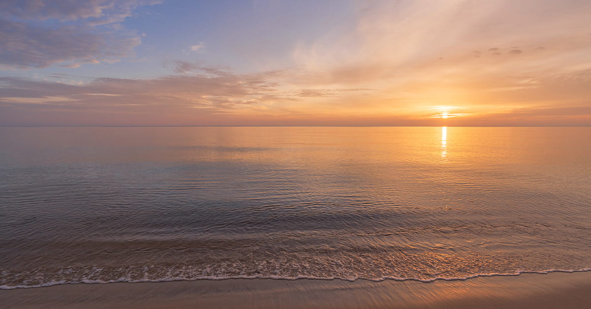 Sunset over calm ocean shoreline