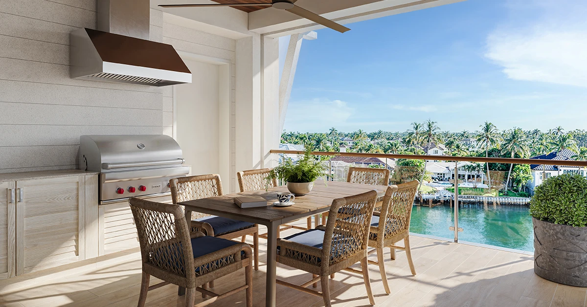 Outdoor terrace with dining table overlooking waterfront and palm trees