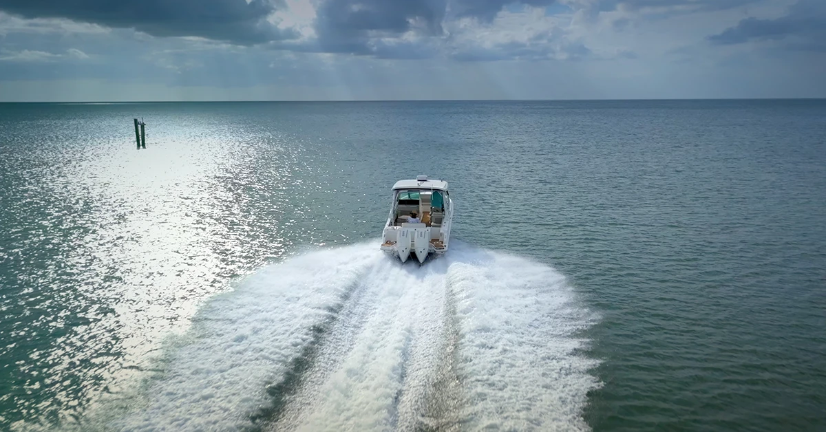 Motorboat speeding across ocean leaving white wake under cloudy sky